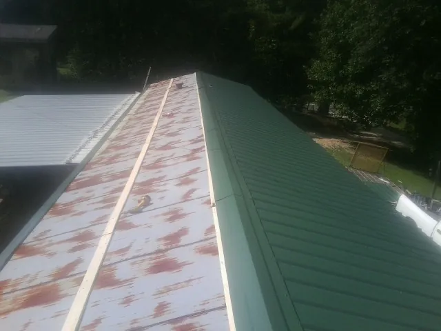 Old rusted panels beside newly installed green metal roofing — Wind Damage Roof Repair by Roofing Brothers in Golden