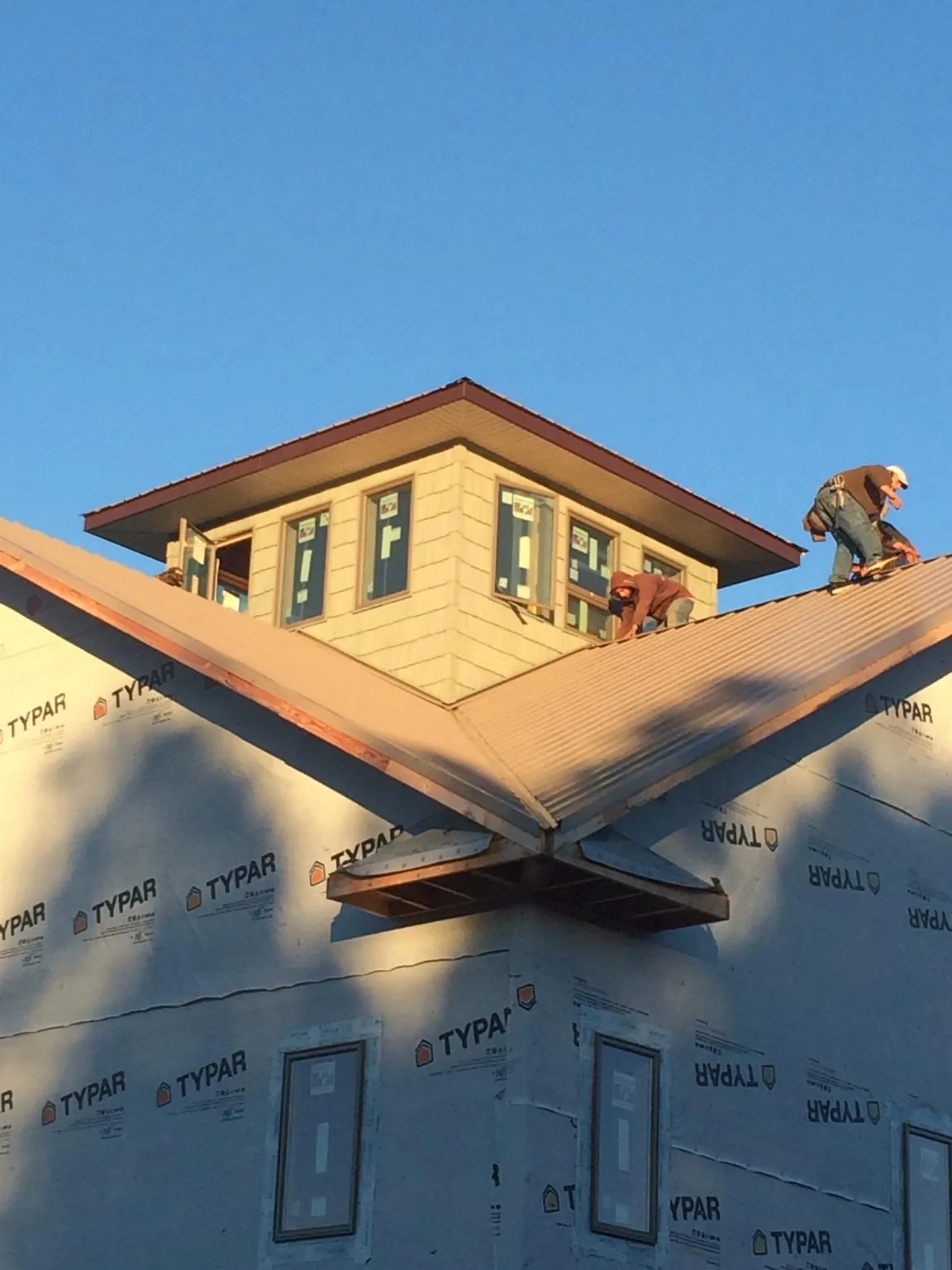Roofers working around a rooftop cupola on a new metal roof at sunset — Roof Waterproofing in Golden by Roofing Brothers